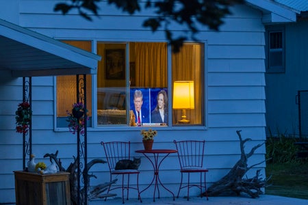 View of a living room through the window of a home where a television can be seen playing the US presidential debate with a split screen of Vice President Kamala Harris and former U.S. President Donald Trump on September 10, 2024