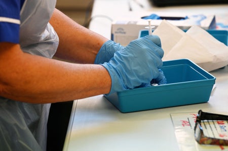 Gloved hands preparing vaccine.