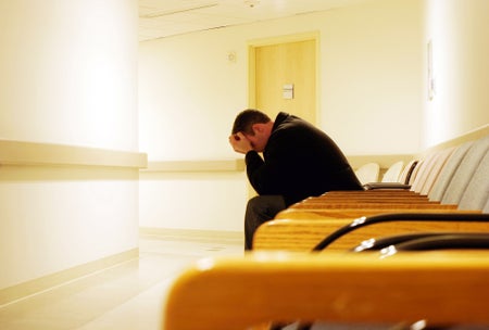 Man alone in hospital, head in hands