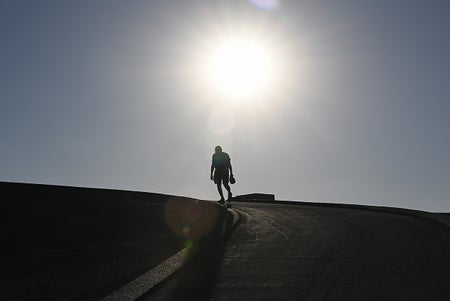 Silhouette of man on hill underneath bright sun