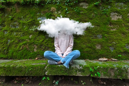 Young and timid woman with head in the cloud sitting on bench