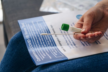 A person holding a swab and vial for a Covid test.