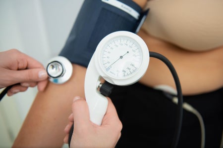 A healthcare professional administers a cardiology test with electrodes and blood pressure cuff.