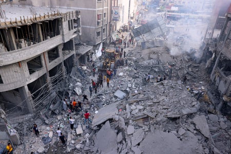 People clearing rubble in a heavily damaged street in Palestine.