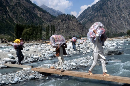 People walking over flood waters with clothing in bags