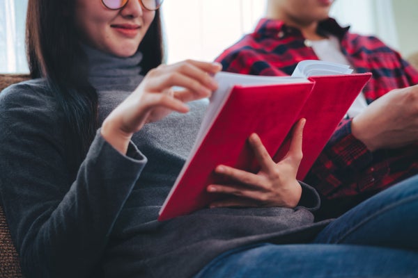 Couple reading on couch & woman holding red book.