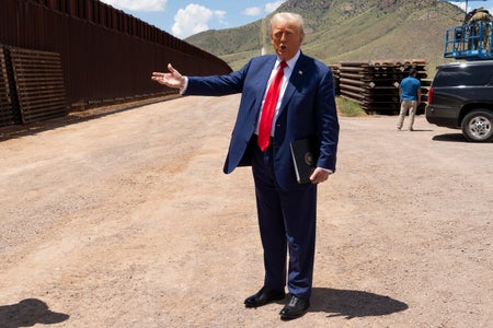 Republican Presidential Candidate and former President Donald Trump stands and gestures at a section of wall at the U.S.-Mexico border on August 22, 2024 south of Sierra Vista, Arizona