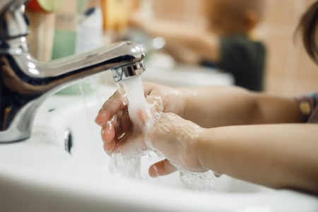 Toddlers wash their hands in a washstand in kindergarten.