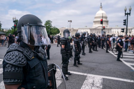 Phalanx of police in riot gear stand guard in street