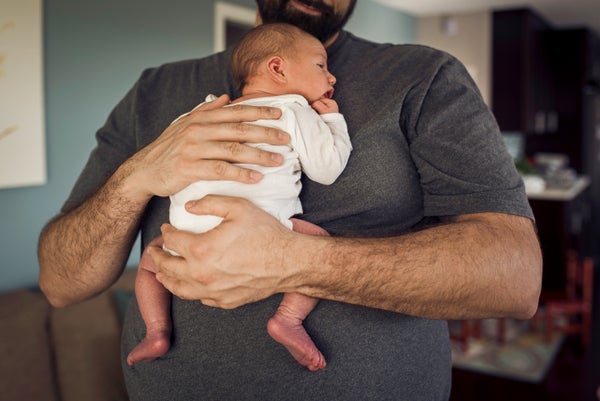 Midsection of father with newborn baby at home