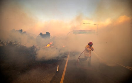 Firefighter with hose in heavy smoke.