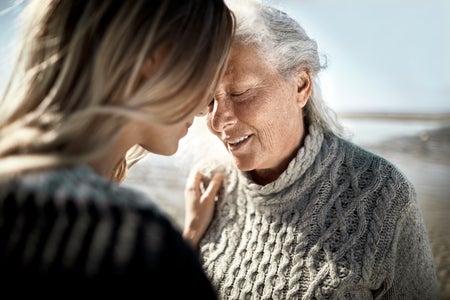 Affectionate senior woman with her adult daughter on the beach