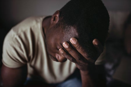 Close-up of black man holding head in hand worriedly