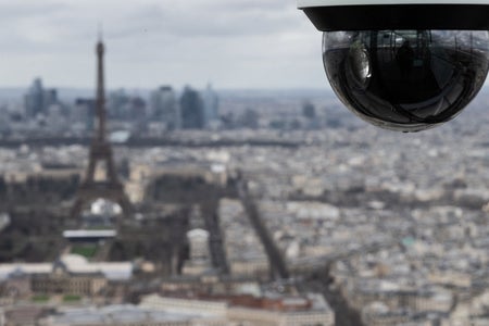 Photo from the rooftop of the Montparnasse Tower in Paris, shows a CCTV surveillance camera with the Eiffel Tower in the background.