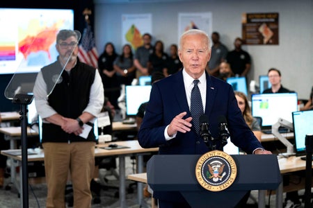 Biden speaks with people from the Emergency Operations center in the background.