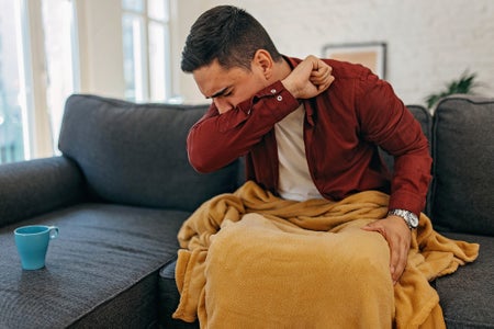 A man coughing into his elbow