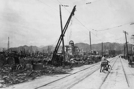 A man wheels his bicycle thorough Hiroshima, Japan, days after the city was leveled by an atomic bomb blast. The Genbaku Dome, now known as the Hiroshima Peace Memorial, and mountains can be seen in the background