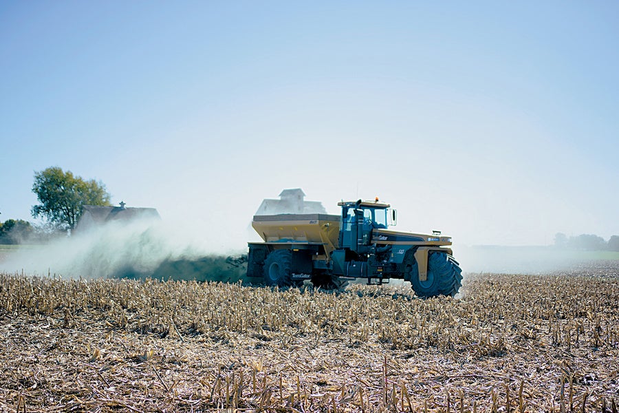 A worker spreads pulverized basalt on a recently harvested cornfield