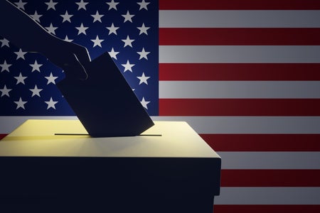 Silhouette of a hand holding a vote putting in a ballot box