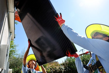 2 workers installing solar panels.